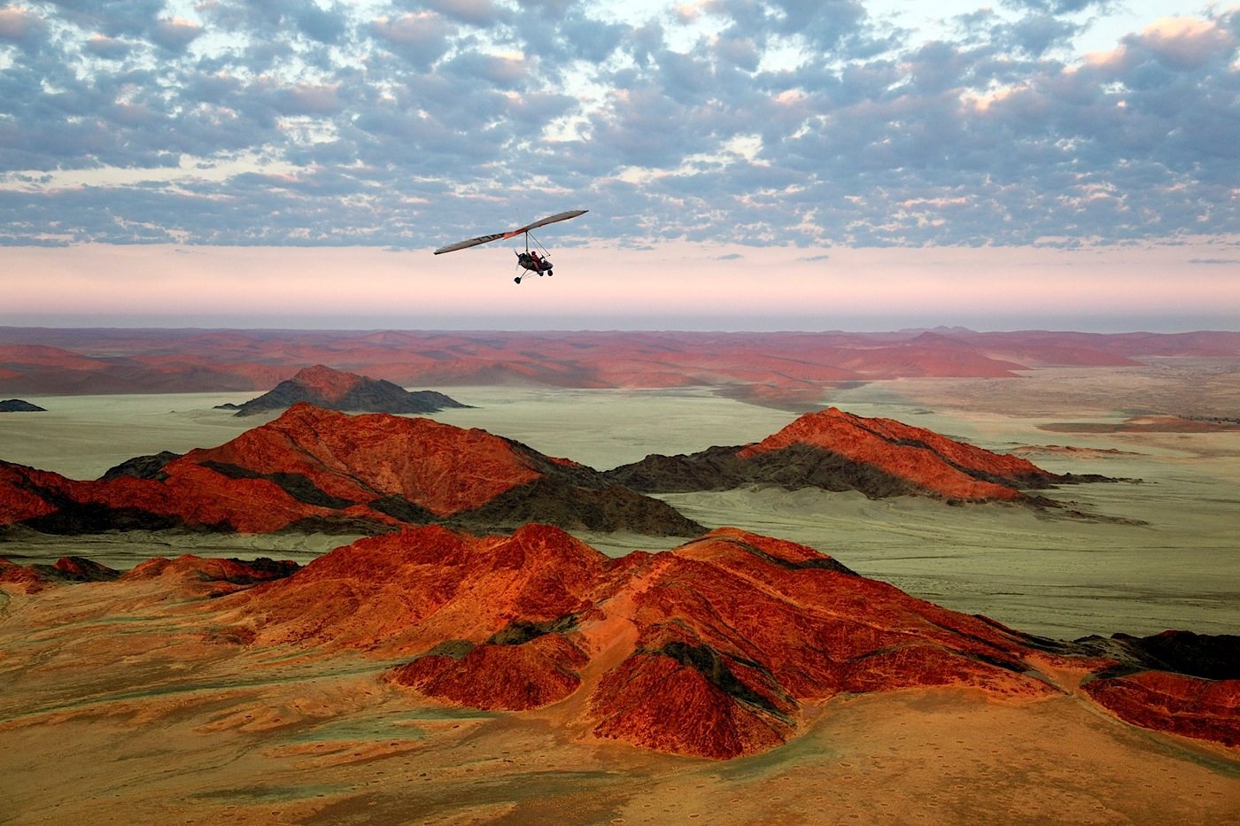 Namibia Flying Microlight flying over the Namib-nuakluft Desert in Namibia at sunrise ...